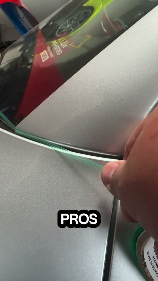 An installer applies knifeless tape and vinyl film into the gap between a vehicle fender and pillar.