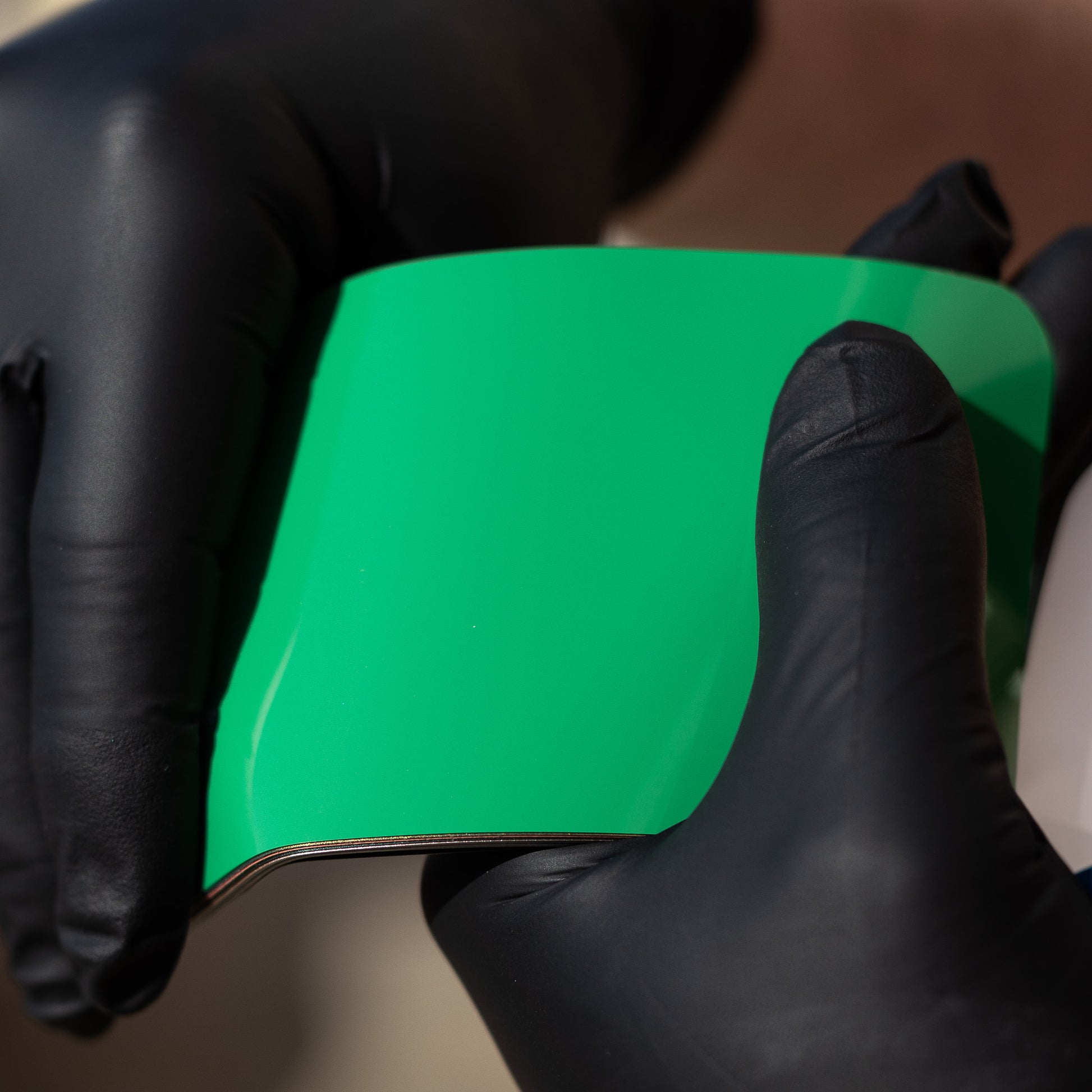 piece of glossy green vinyl wrap or paint protection film (PPF)