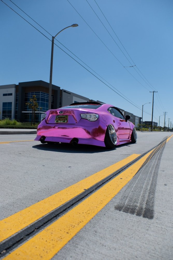 Pink car on a city street with clear blue sky